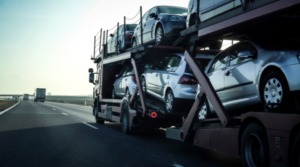 Image of a car trailer loaded with vehicles, illustrating vehicle transport options: open vs. enclosed carriers